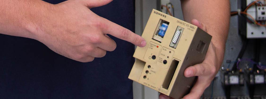 Person holding and pointing to a Siemens SIMATIC S5-100U industrial control module.